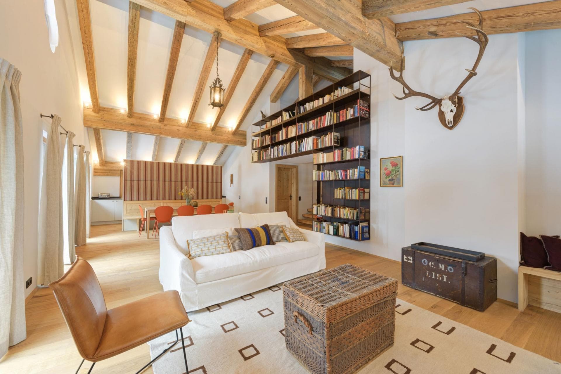 Open-plan living area with vaulted timber beams and library wall