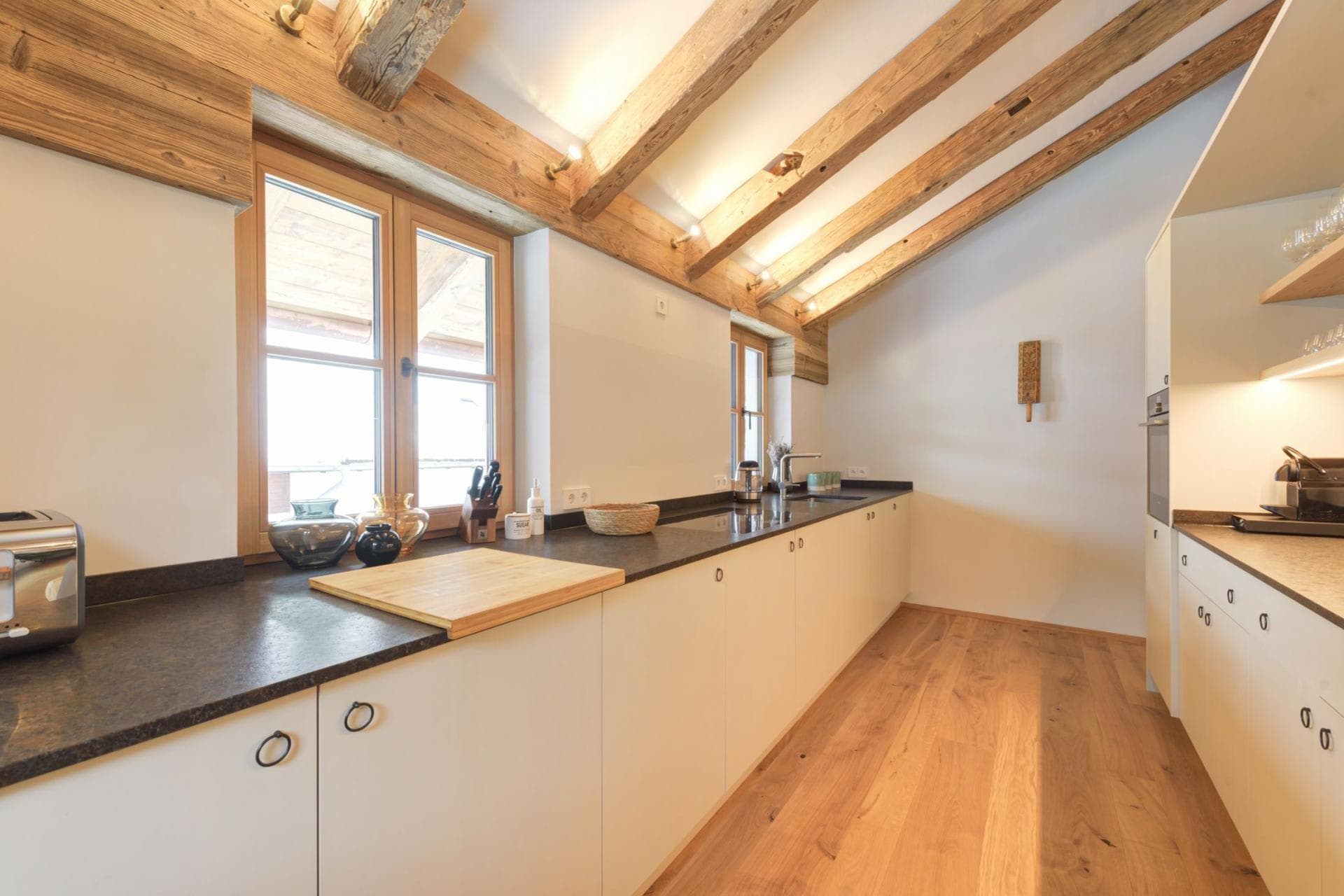 Galley kitchen with induction cooktop and reclaimed timber ceiling beams