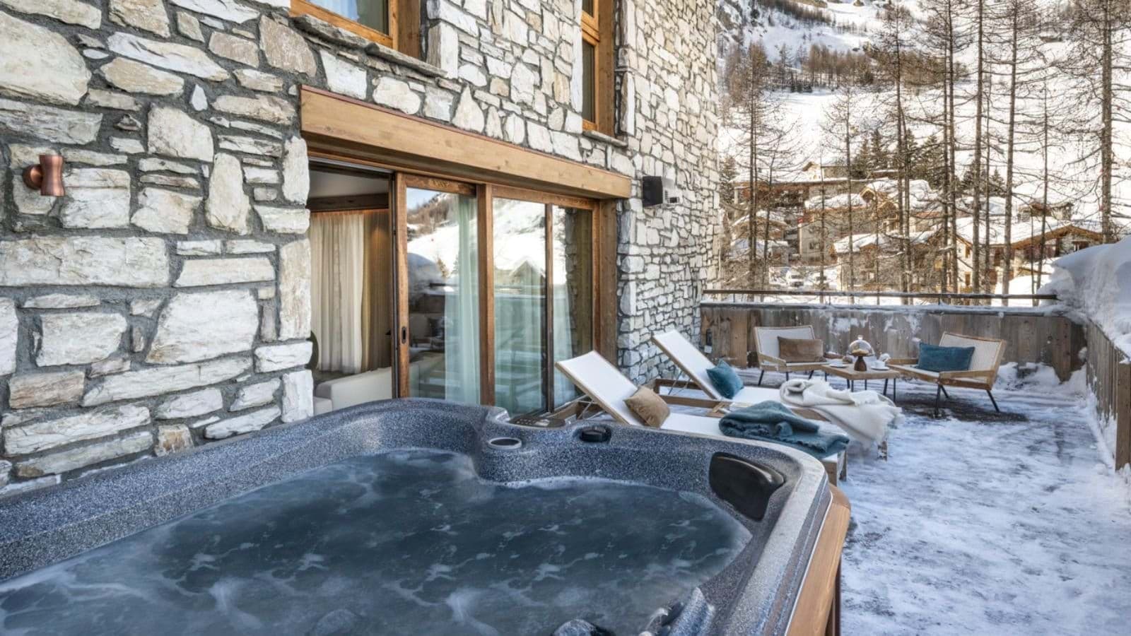 Private terrace with outdoor hot tub, sun loungers, and mountain views