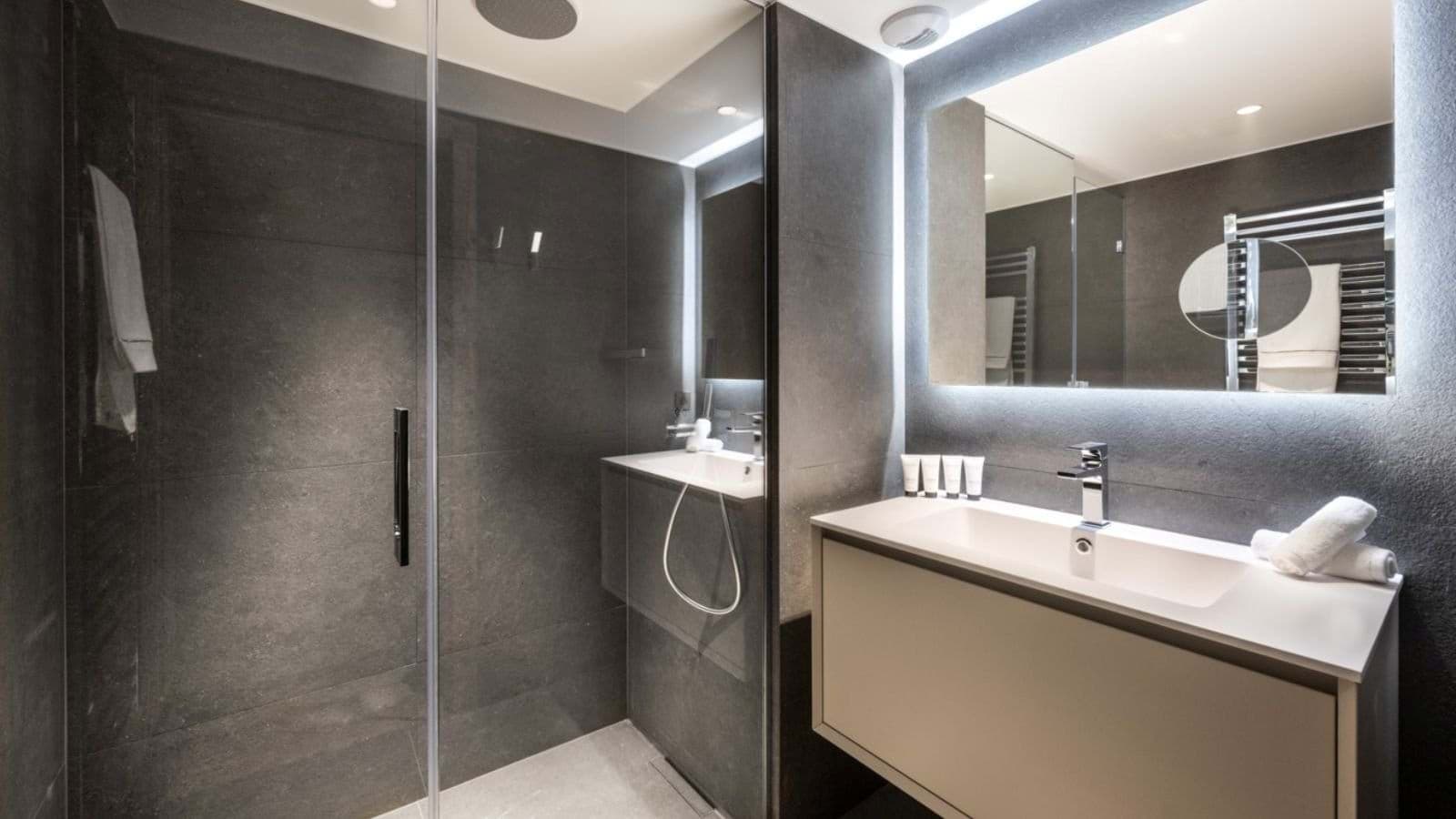 Bathroom with walk-in rainfall shower and backlit vanity mirror