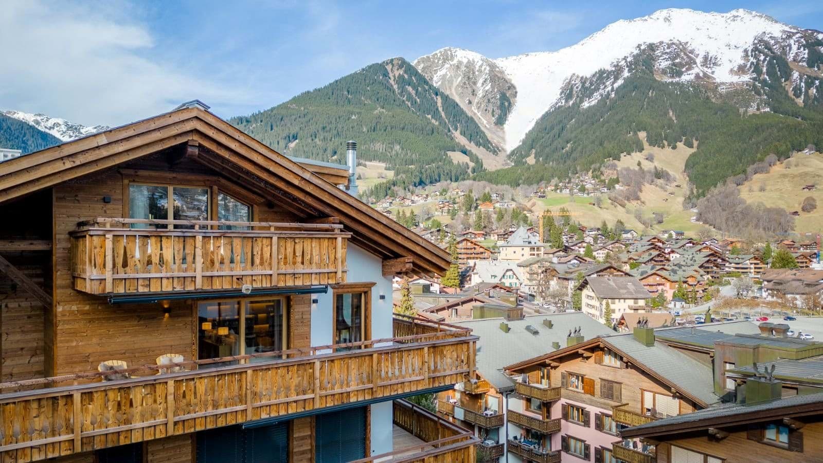 Multi-level wooden balconies overlooking Alpine village and snowy peaks