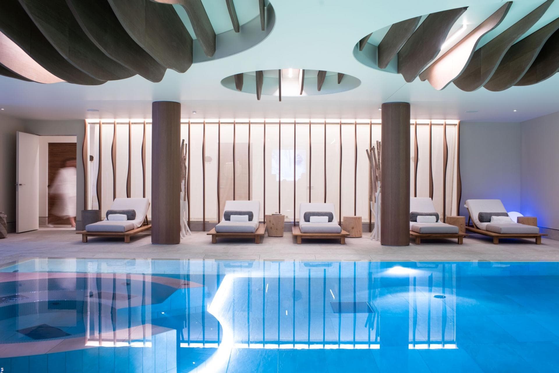 Indoor pool and spa area with five padded loungers
