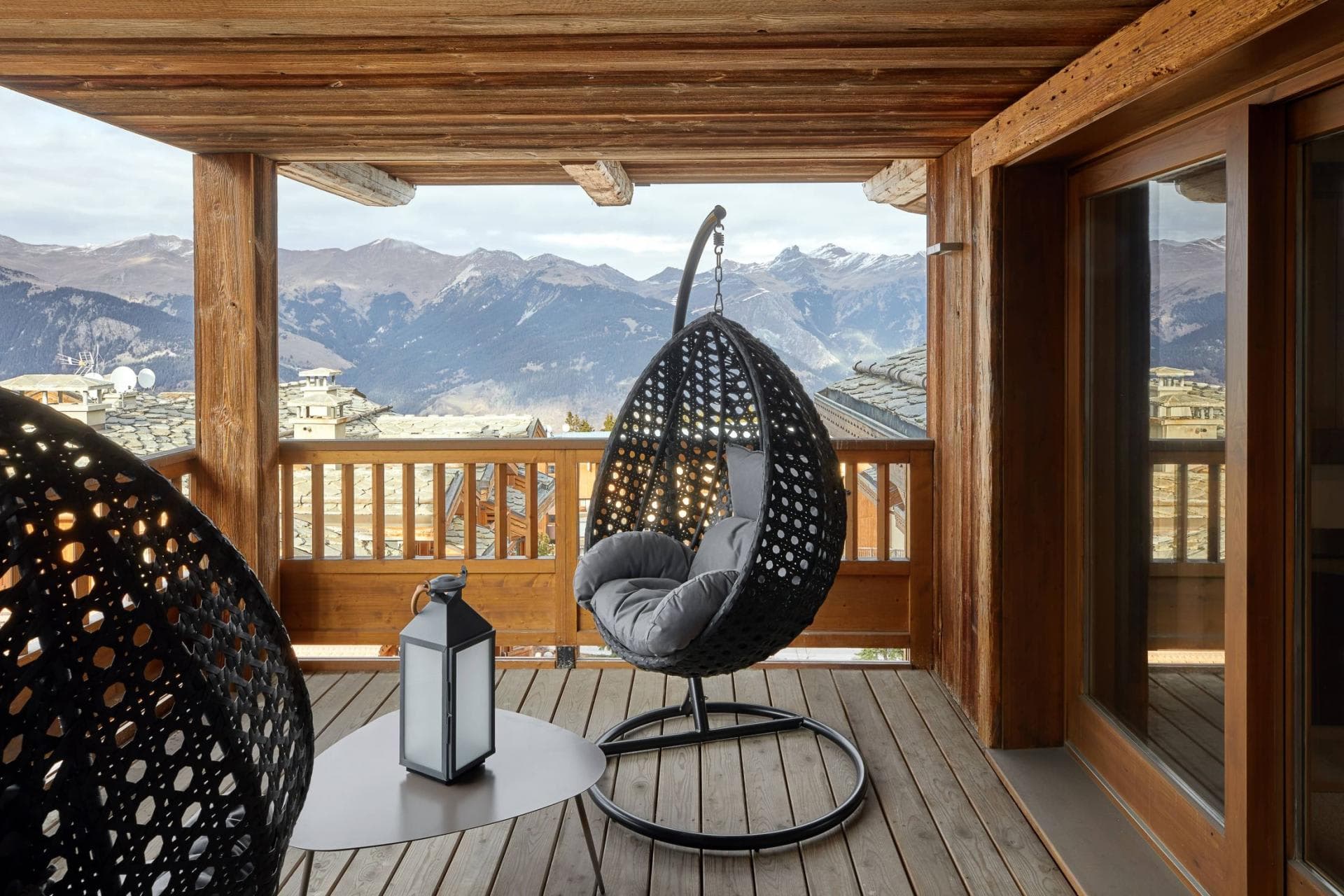 Covered timber balcony with hanging egg chairs and panoramic mountain views