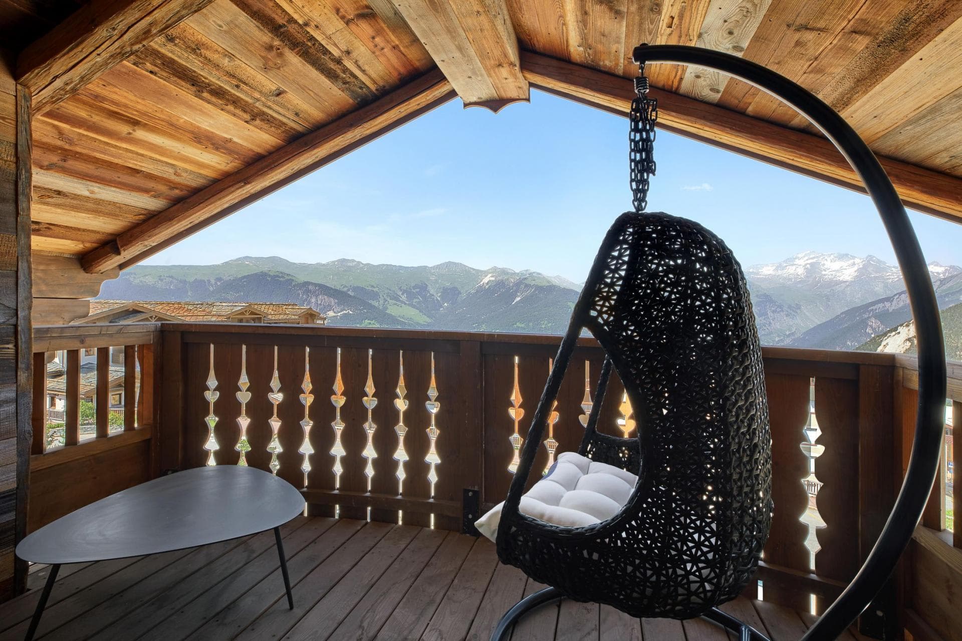 Covered balcony with hanging egg chair and panoramic mountain views