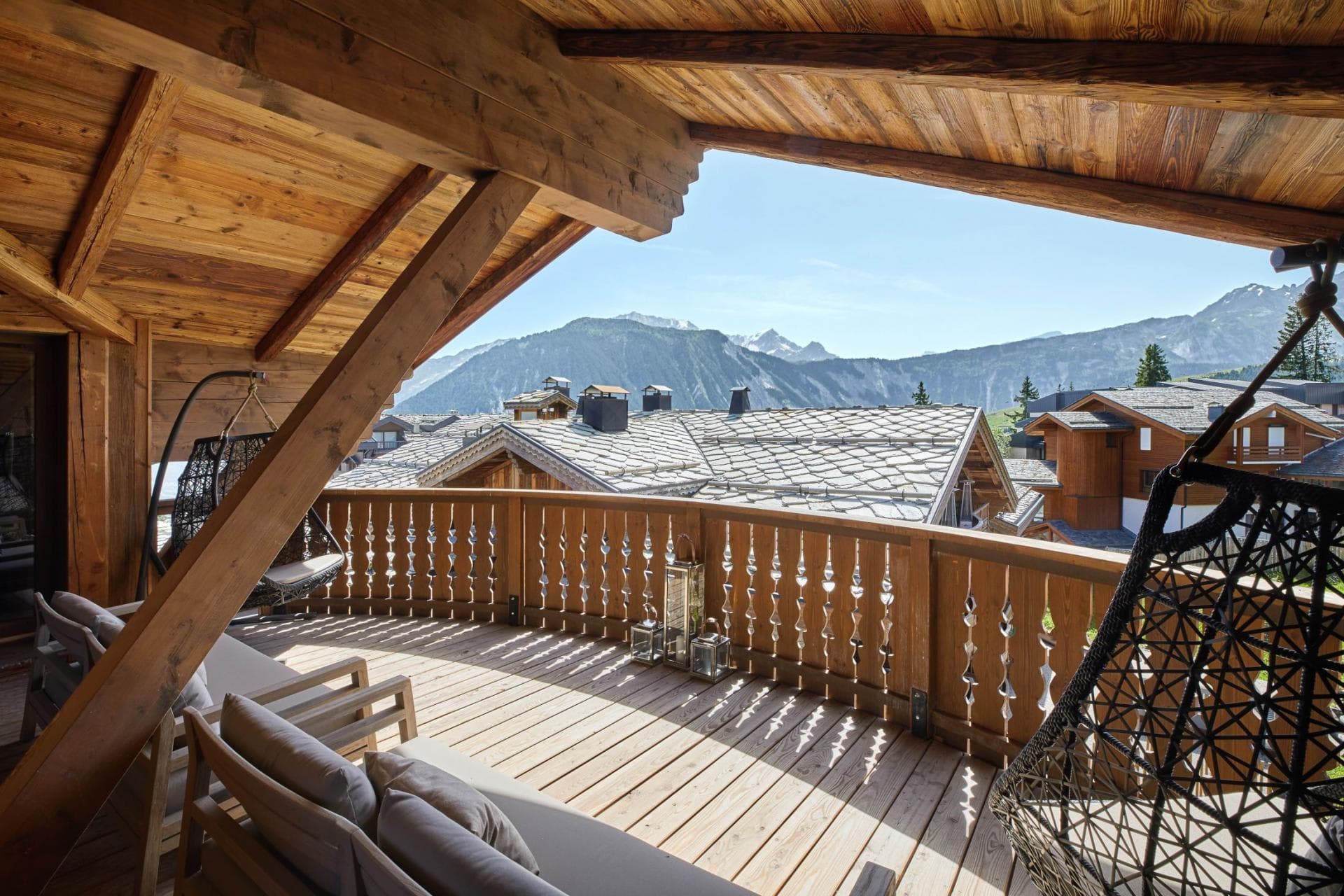 Covered balcony with hanging egg chairs and mountain views