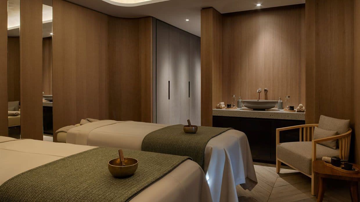 Treatment room with dual massage tables and stone vanity