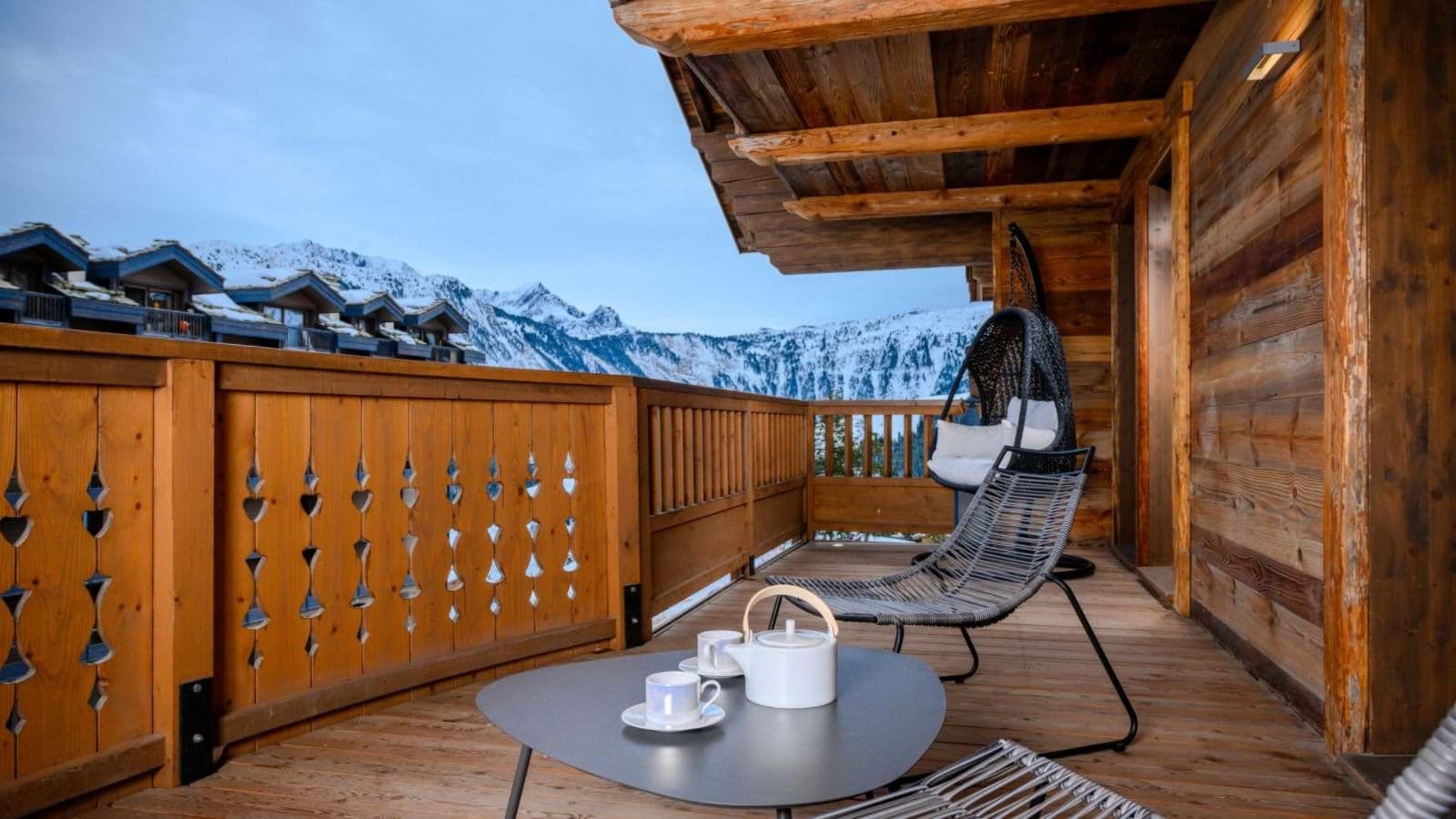 Private timber balcony with hanging egg chair and panoramic alpine views