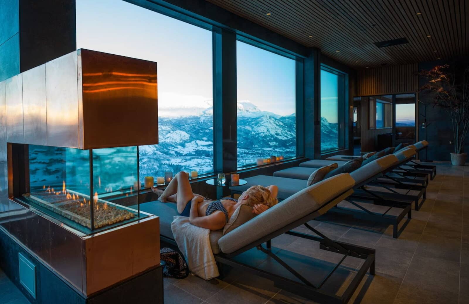 Indoor lounge with gas fireplace and floor-to-ceiling mountain views