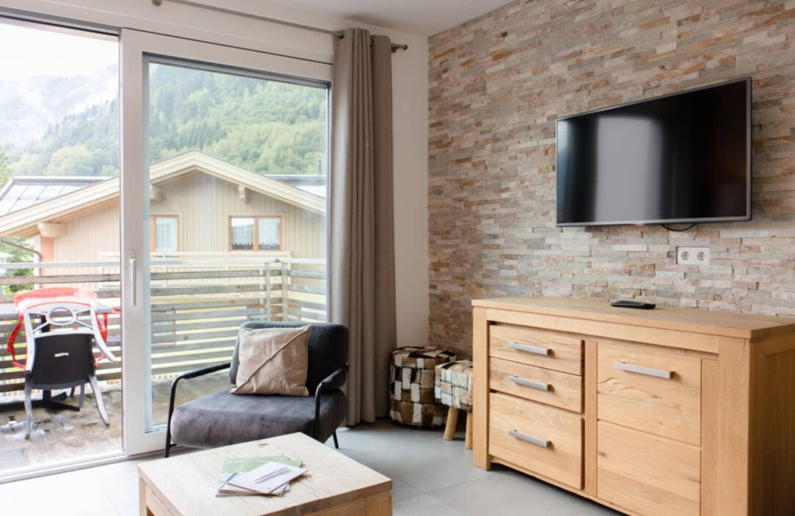 Living area with wall-mounted TV and sliding door to mountain-view balcony