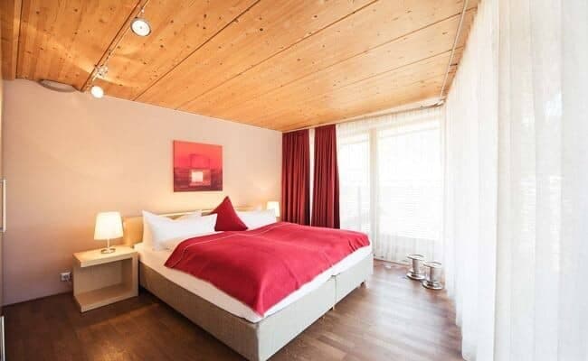 Bedroom with king bed, timber ceiling, and floor-to-ceiling windows