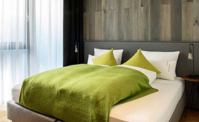 Bedroom with queen bed, wood paneled wall, and bedside reading lamps