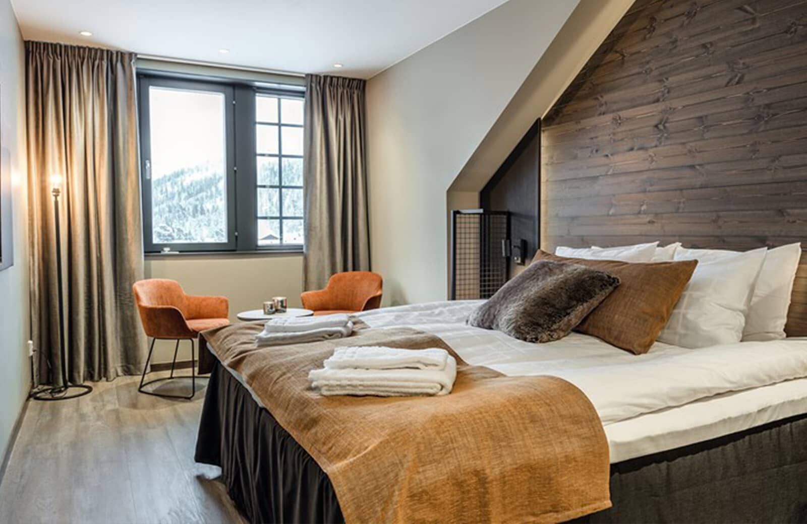 Bedroom with king bed and seating area; snowy mountain views