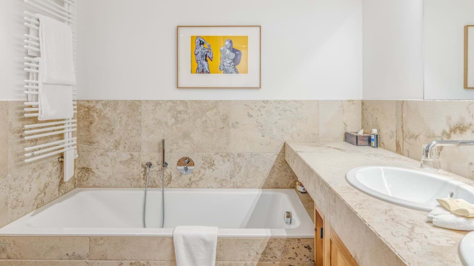 Bathroom featuring soaking tub with hand shower and heated towel rack