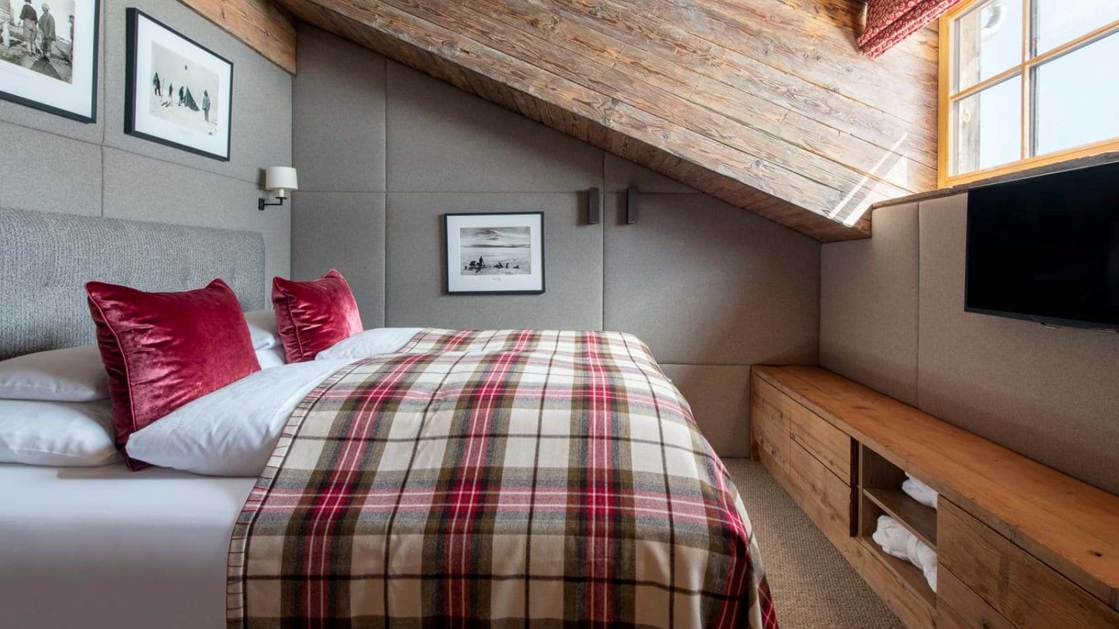 Attic bedroom with queen bed and built-in storage under sloped timber ceiling