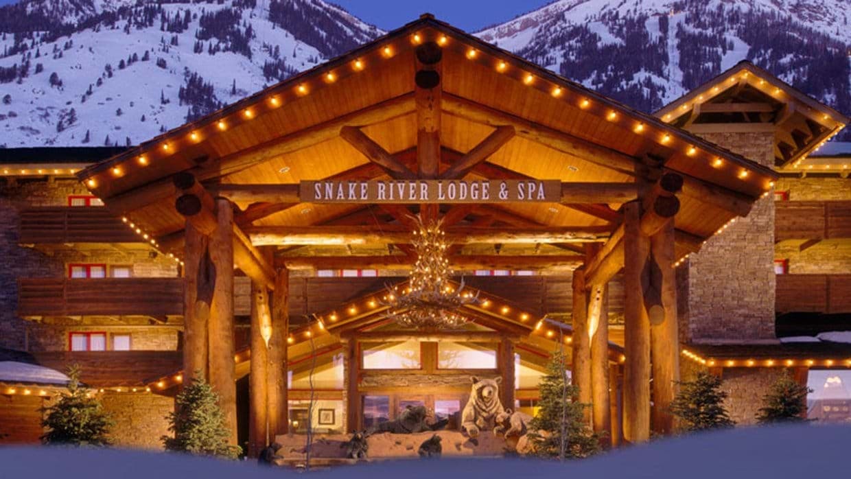 Lodge entrance with timber porte-cochère and antler chandelier at base of ski mountain