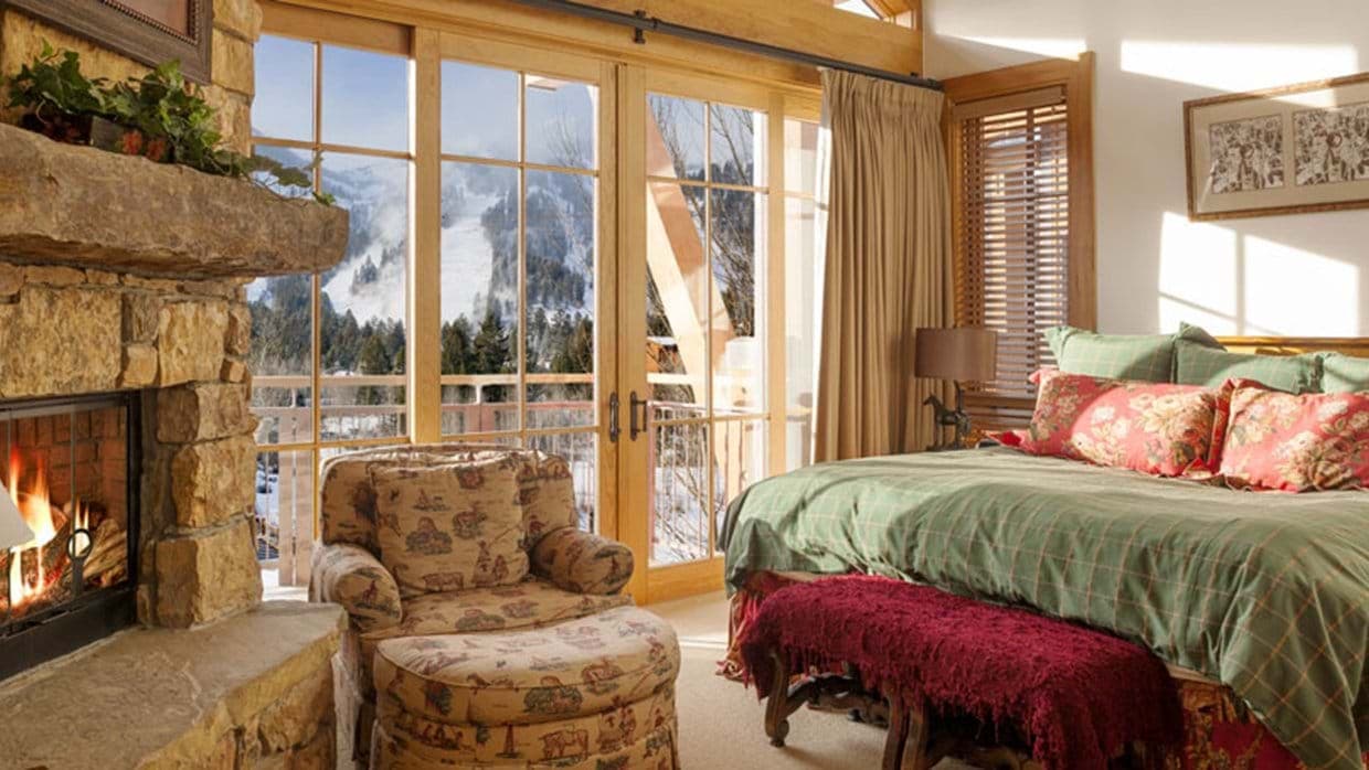 Primary bedroom with stone fireplace and ski slope views