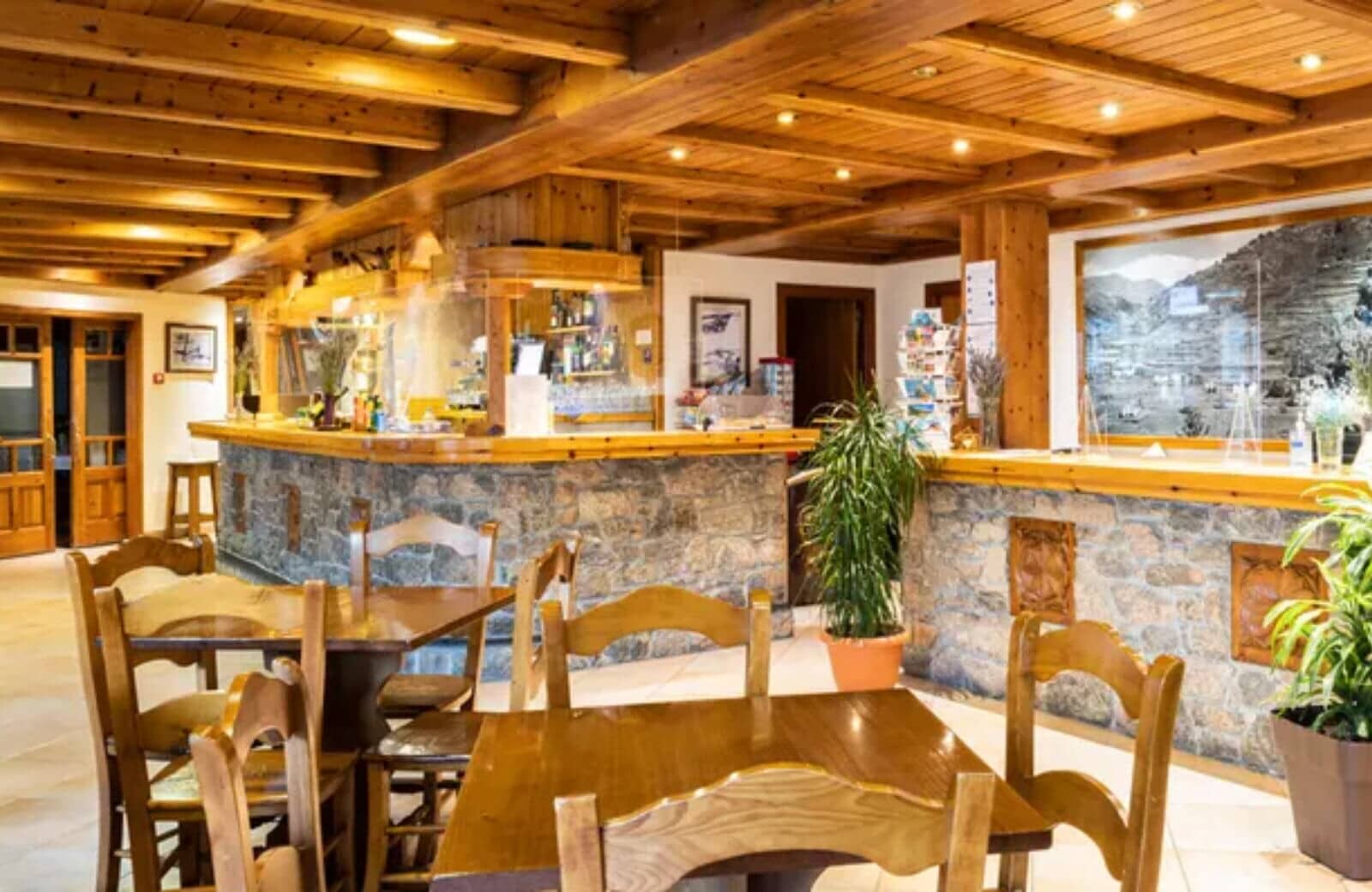 Bar and dining area with stone accents and wood beam ceiling