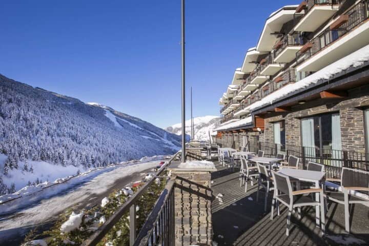 Outdoor terrace with multiple dining tables and ski slope views