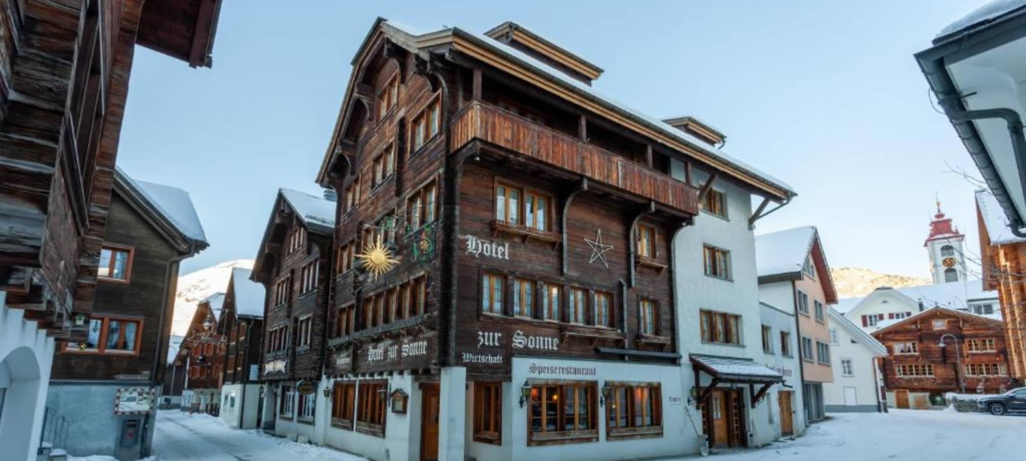 Traditional timber chalet exterior with ground-floor restaurant and private balconies