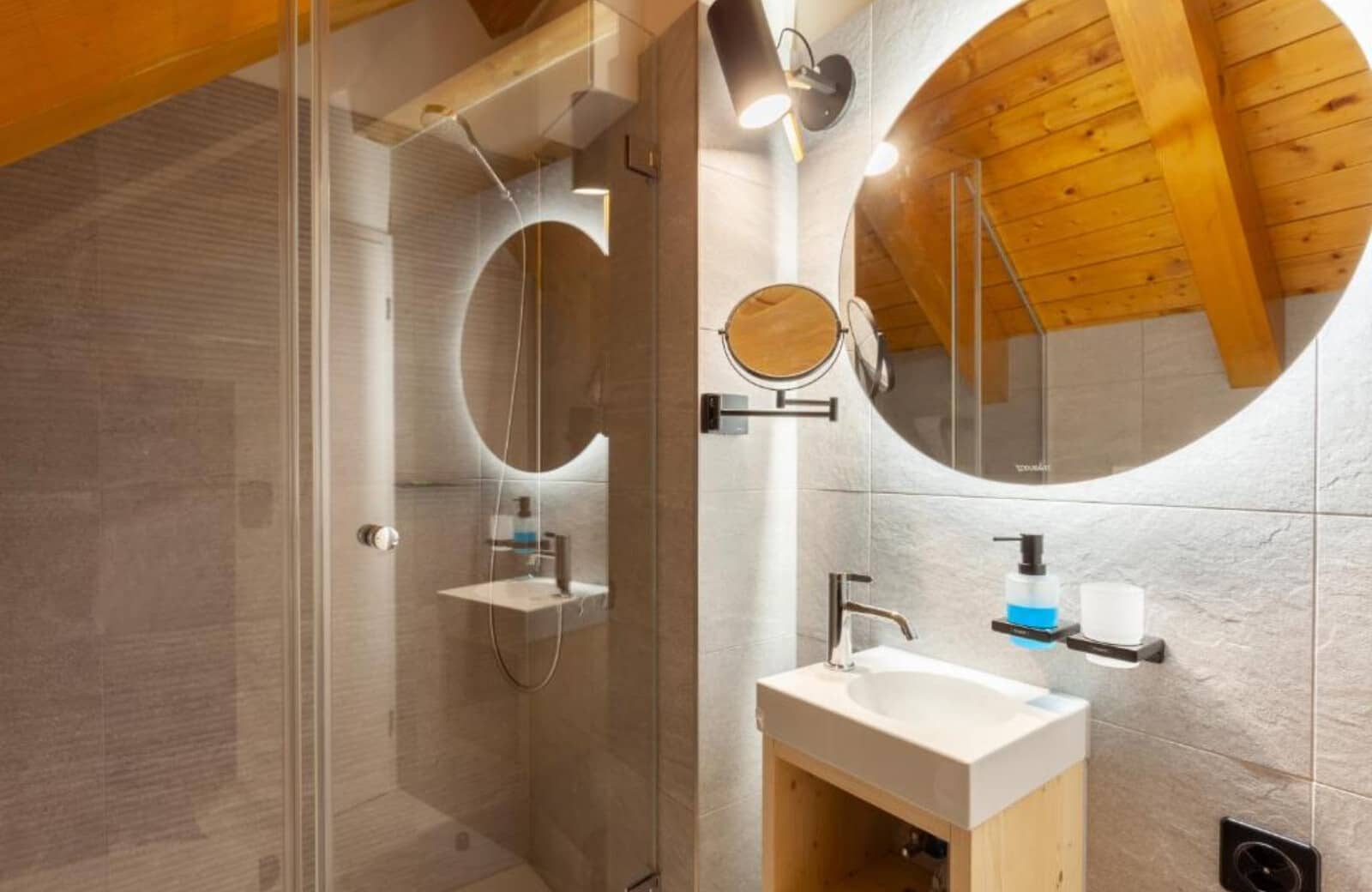 Bathroom featuring walk-in glass shower and backlit vanity mirror