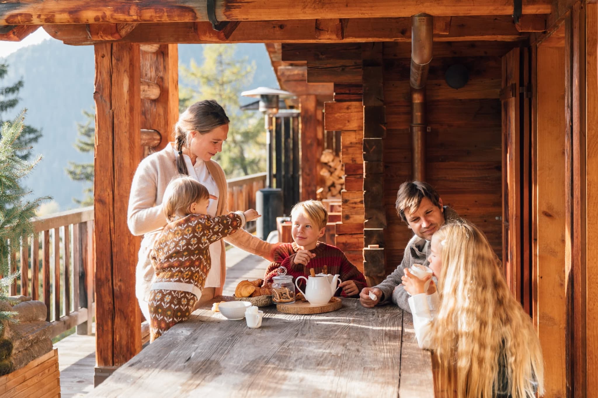 Covered log cabin terrace with outdoor dining and valley views