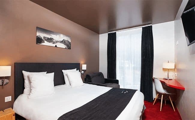 Bedroom with king bed, armchair, and dedicated workspace with desk