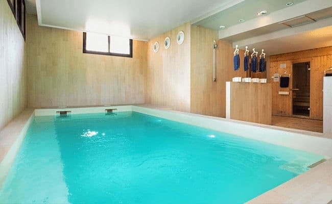 Indoor swimming pool and wood-paneled sauna room