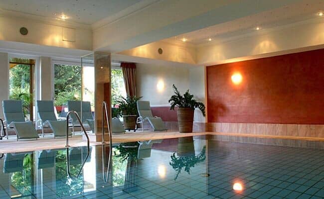 Indoor pool with poolside loungers and garden views