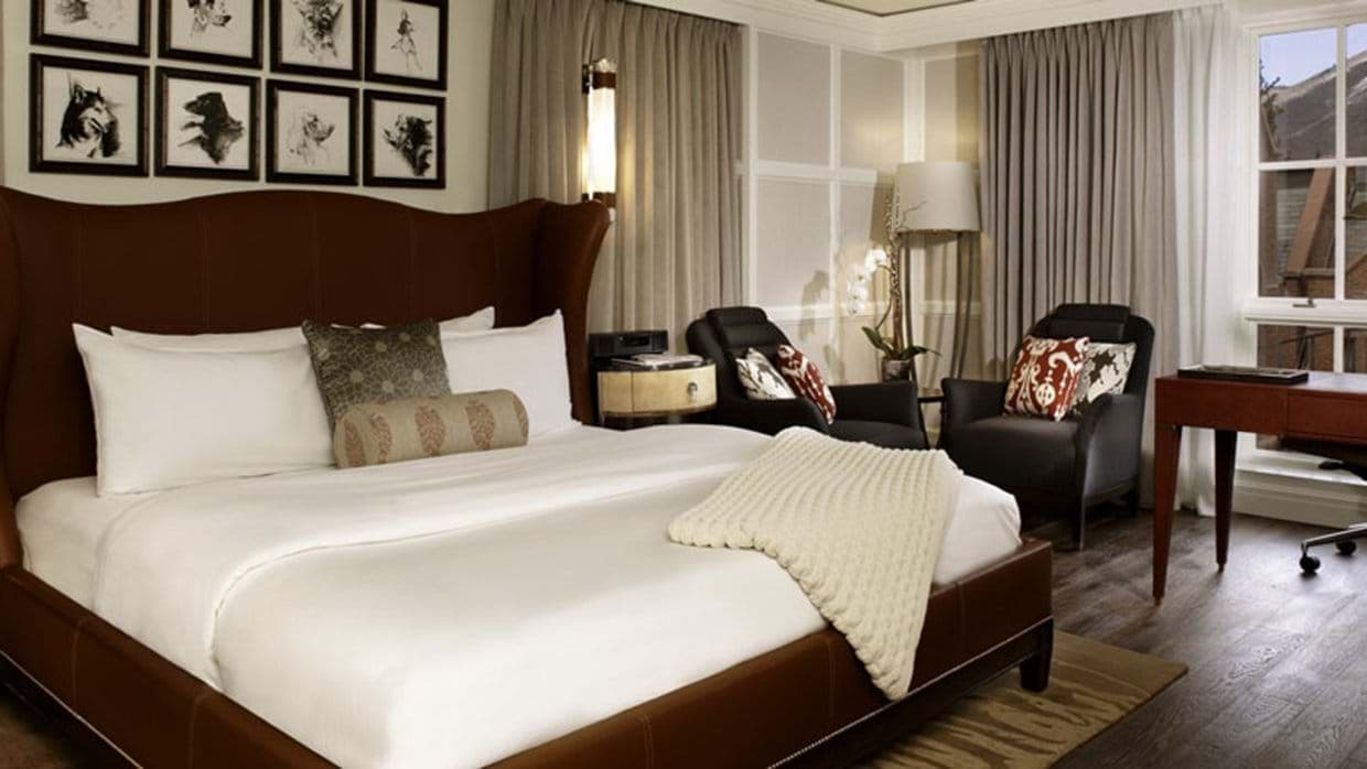 Primary bedroom with king bed, armchairs, and dedicated workspace