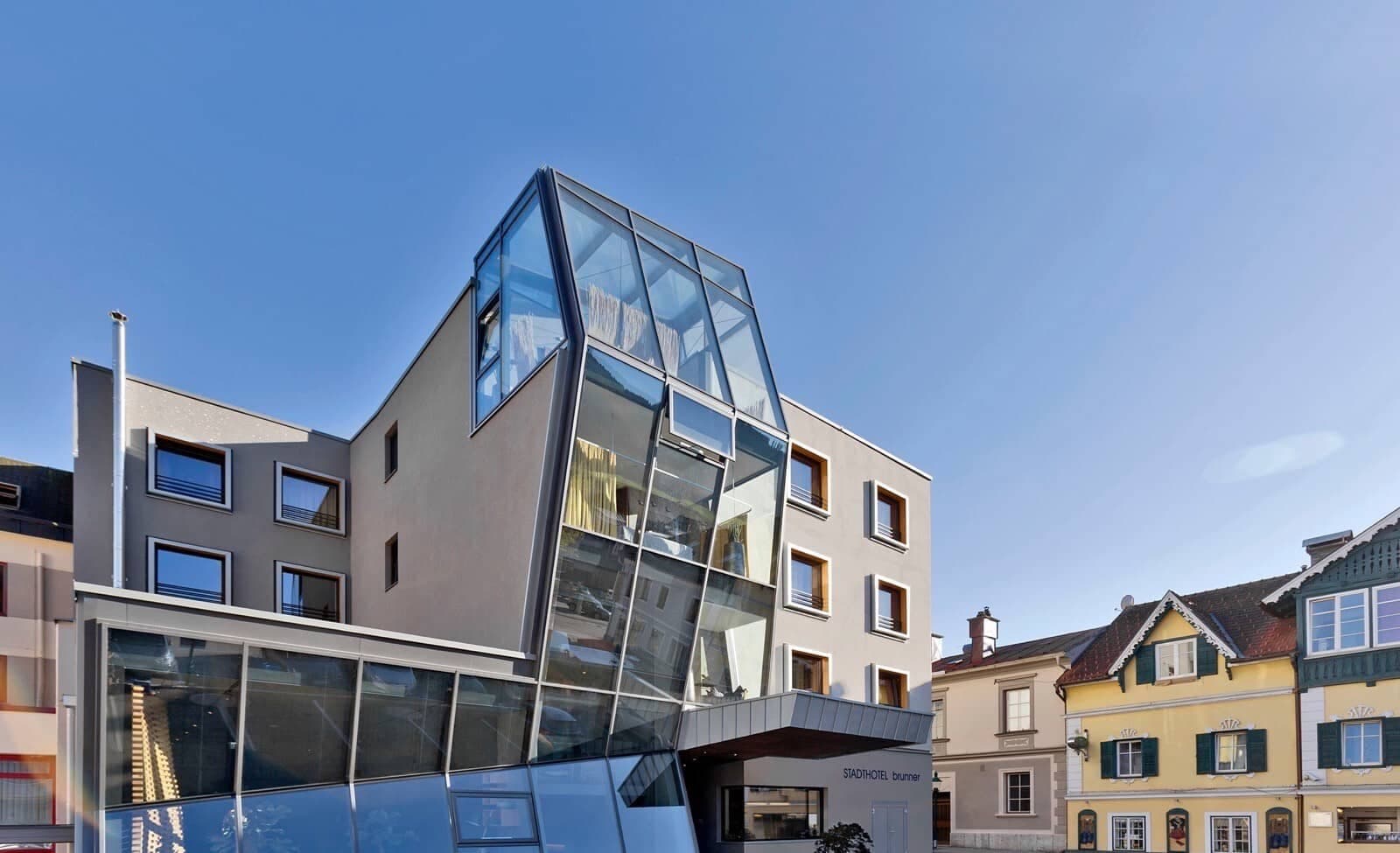 Hotel exterior featuring floor-to-ceiling glass solarium and rooftop terrace