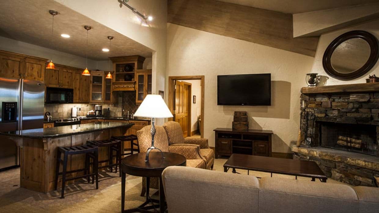 Open living area with stone fireplace and kitchen island seating