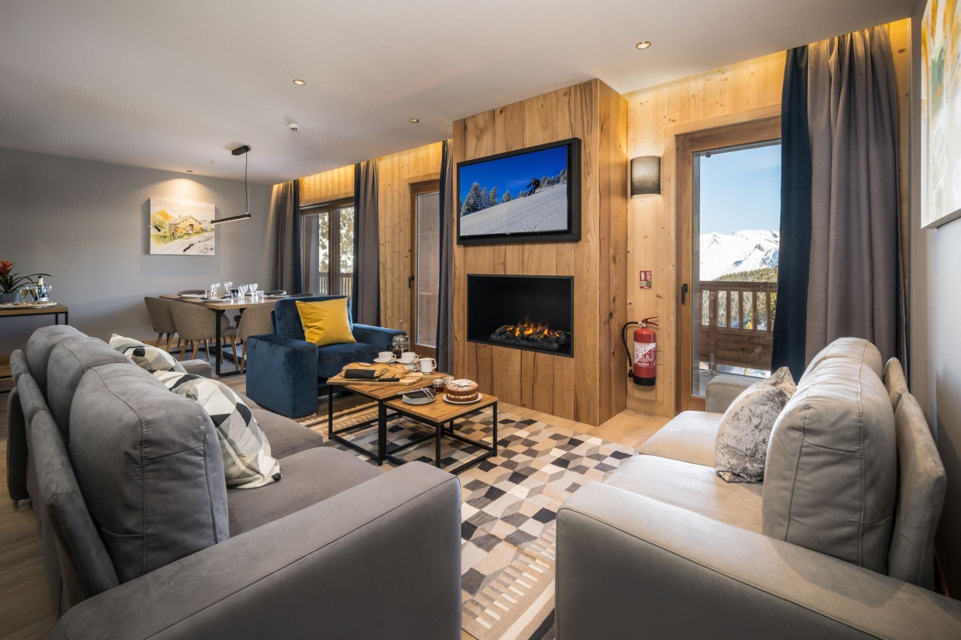 Living area with electric fireplace and balcony access; mountain views