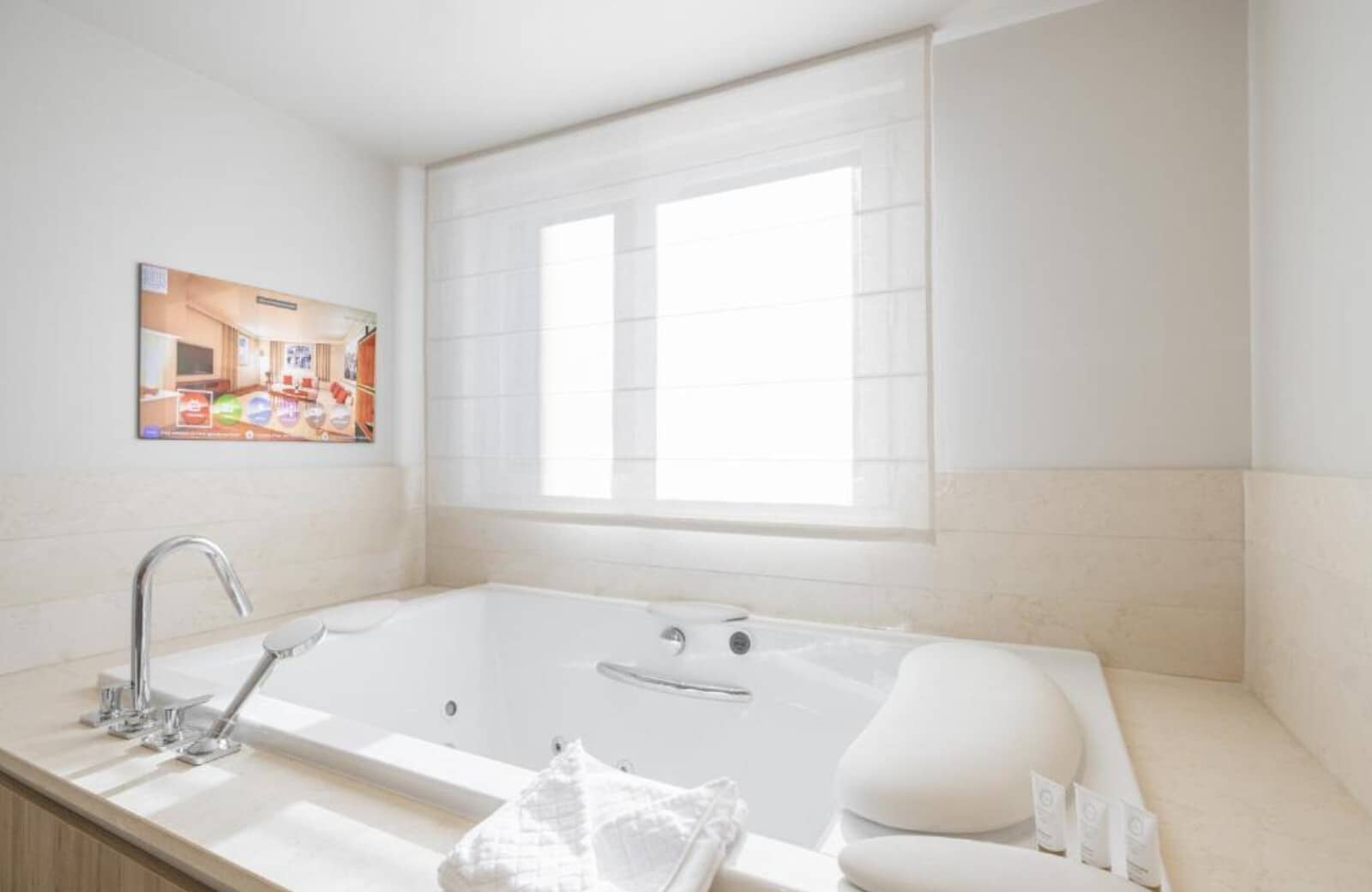 Jetted soaking tub with integrated headrest and wall-mounted TV