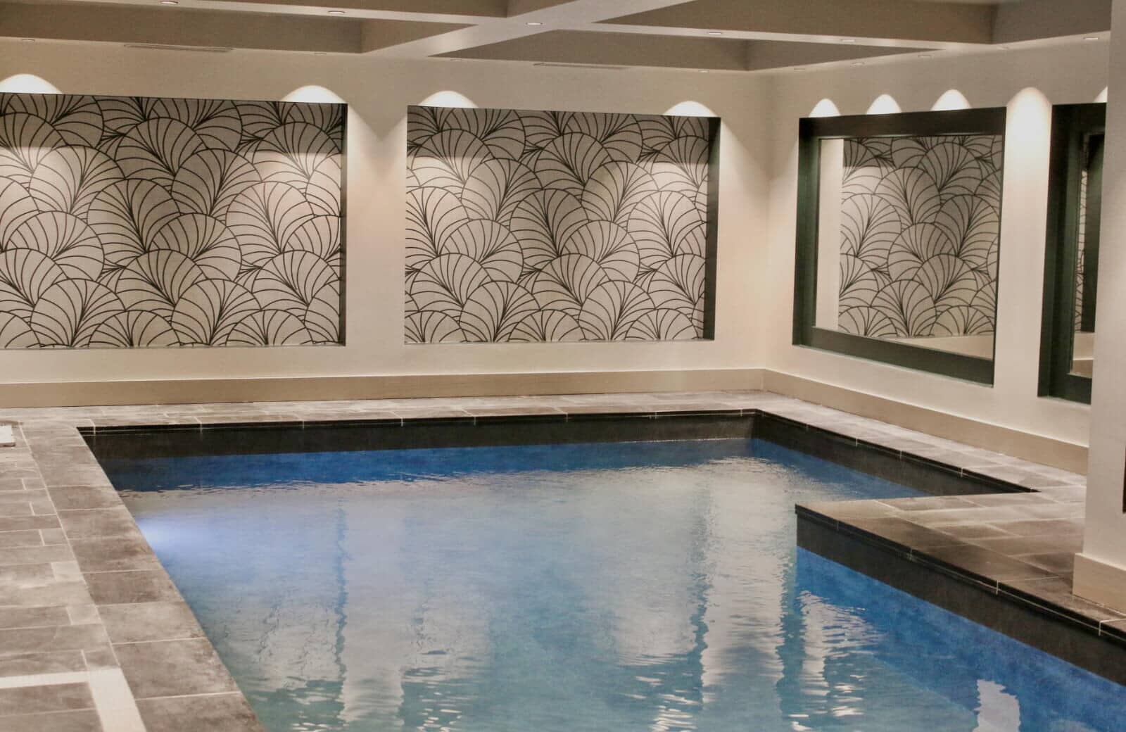 Indoor heated pool with recessed lighting and art deco wall details