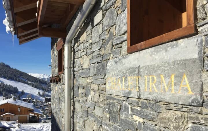 Stone chalet exterior with engraved nameplate and alpine valley views