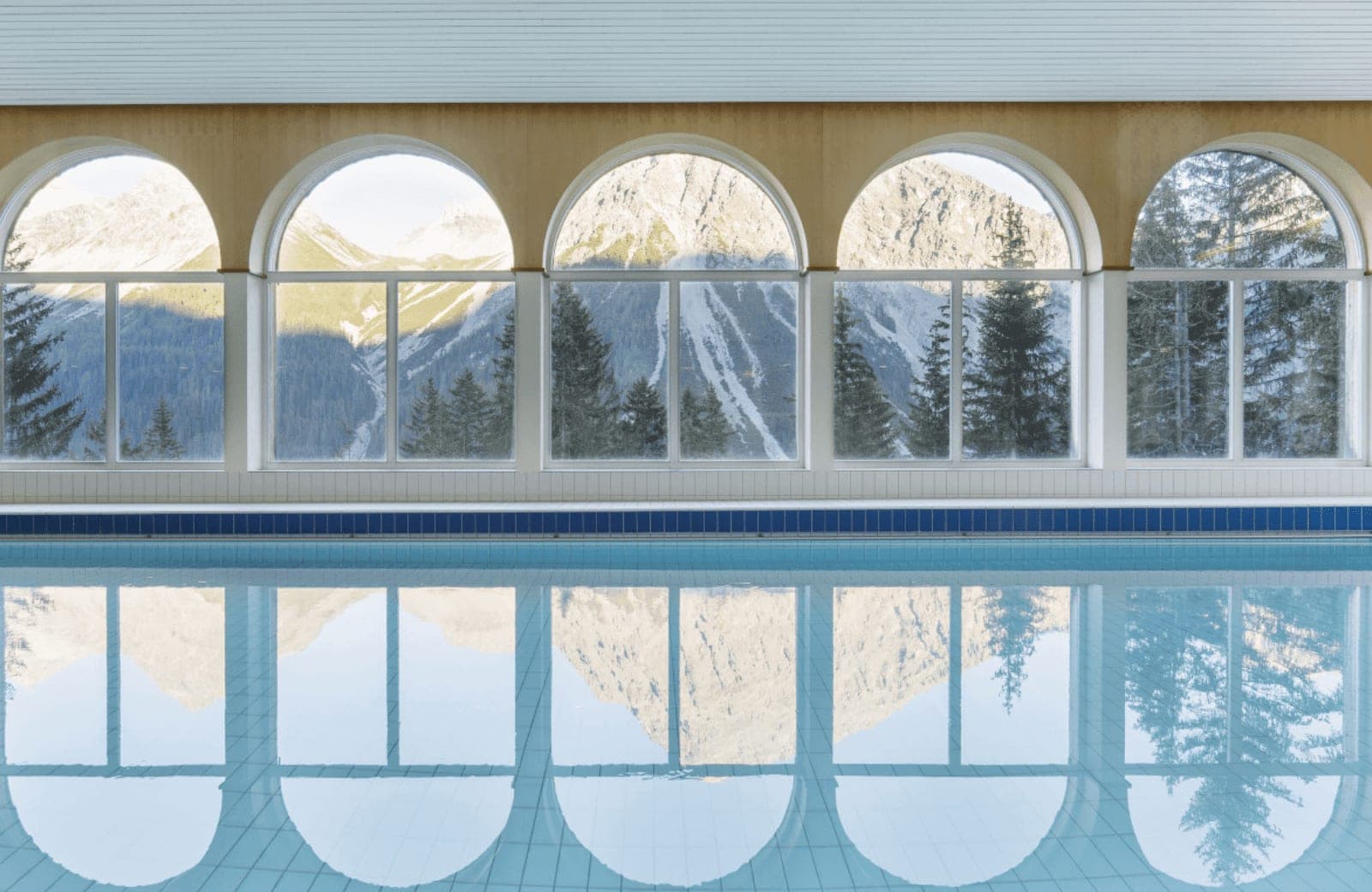 Indoor pool with arched windows and mountain views