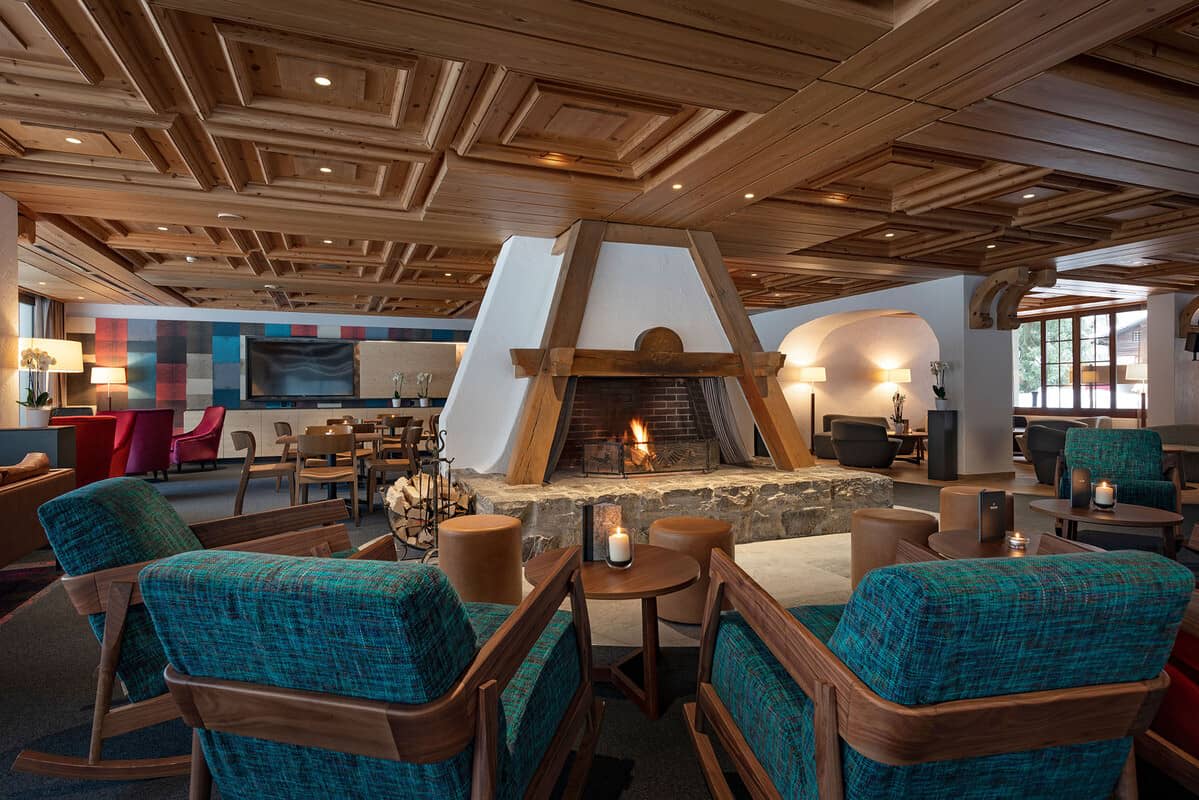 Lounge area with central stone fireplace and hand-carved wood ceilings