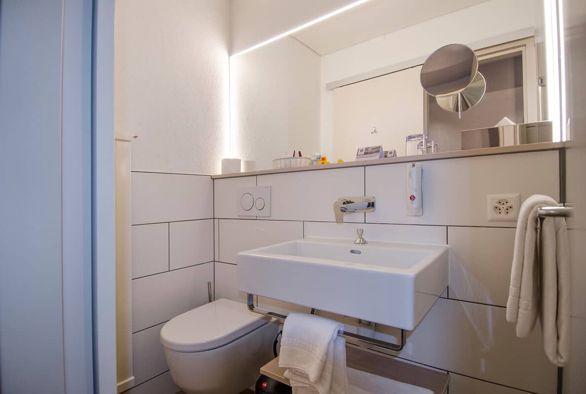 Bathroom featuring vessel sink and backlit vanity mirror