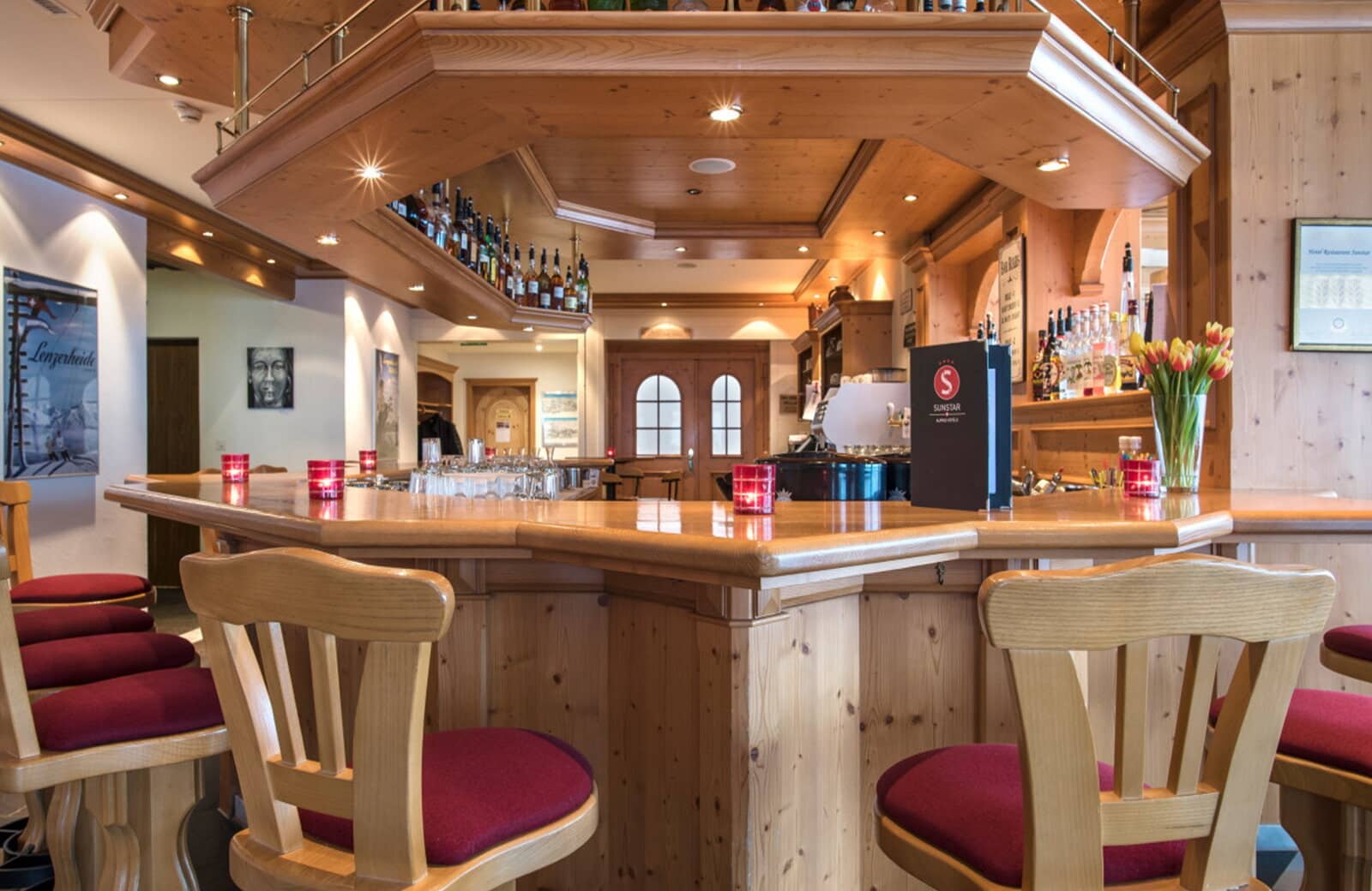 Wood-paneled lounge bar with stool seating and overhead bottle storage
