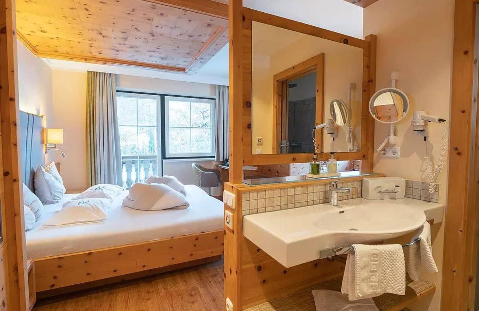 Open-concept bedroom and bathroom with vanity, king bed, and balcony