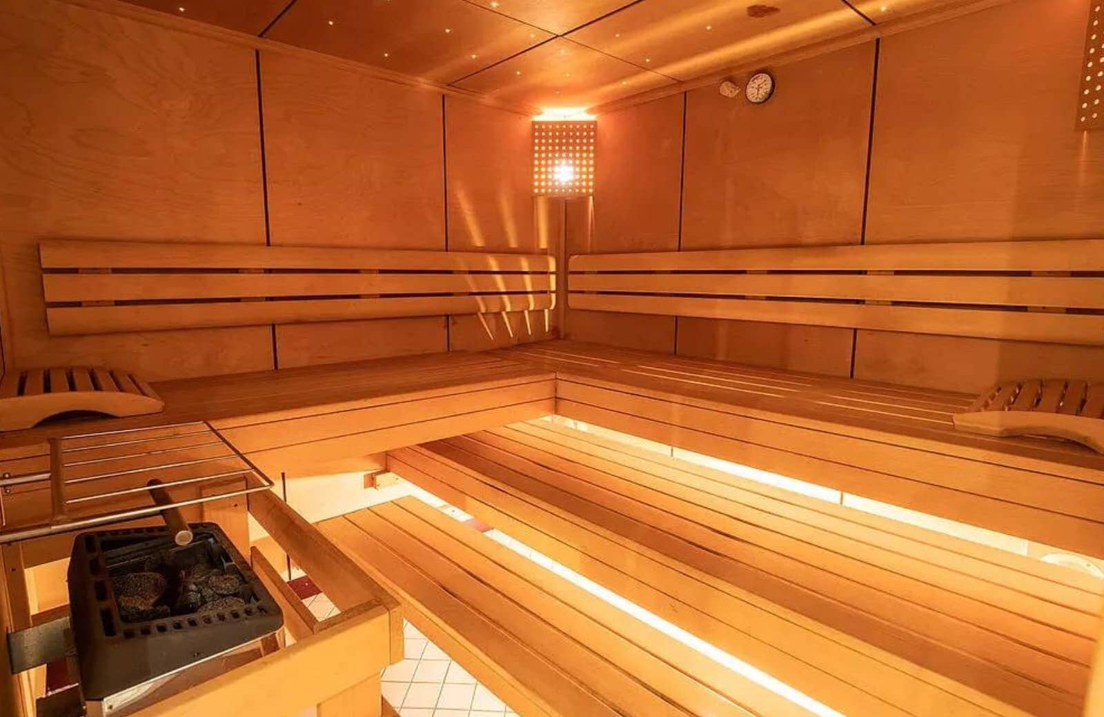 Private sauna with tiered bench seating and electric rock heater