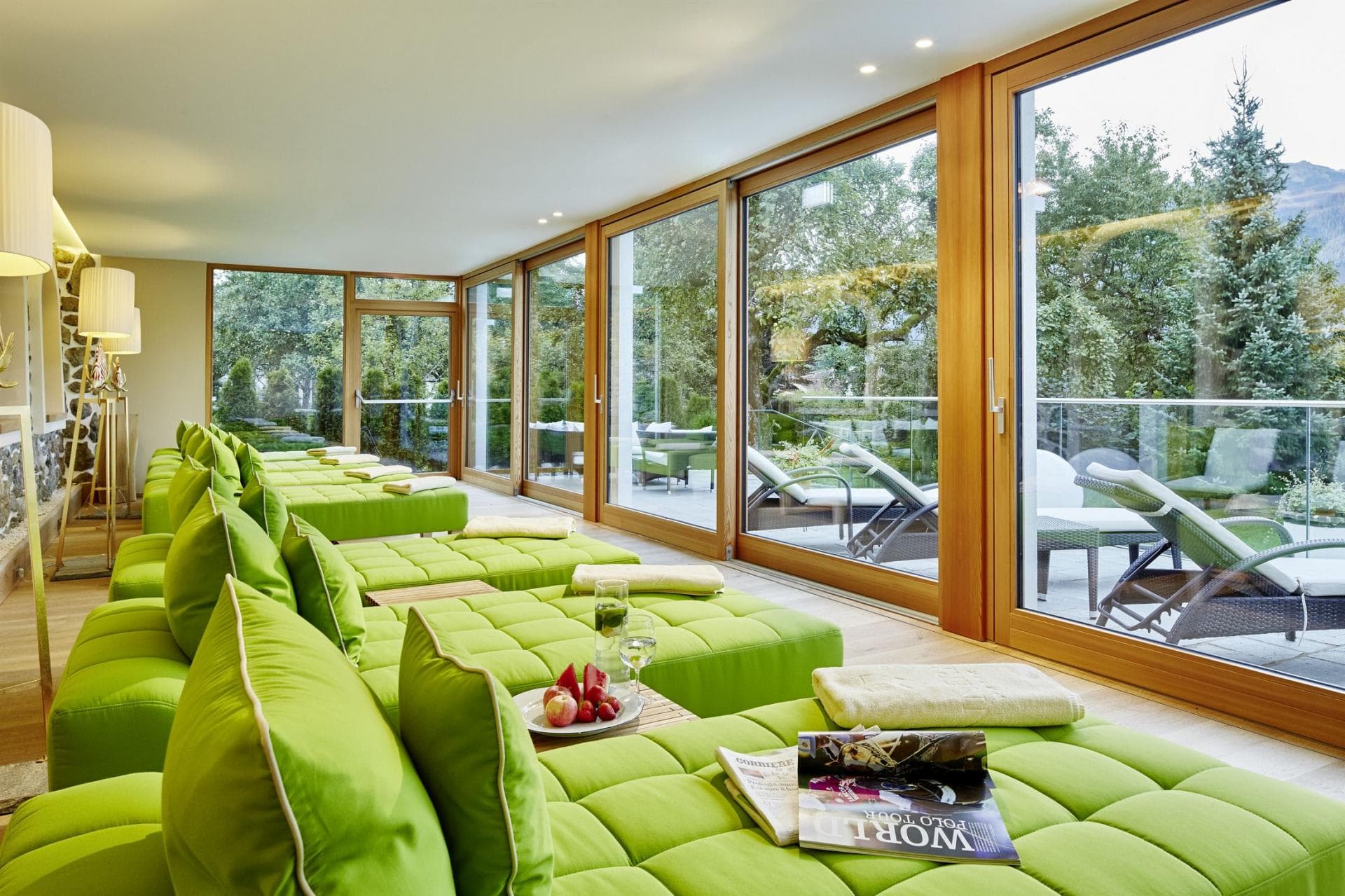 Spa lounge with tufted daybeds and floor-to-ceiling garden views