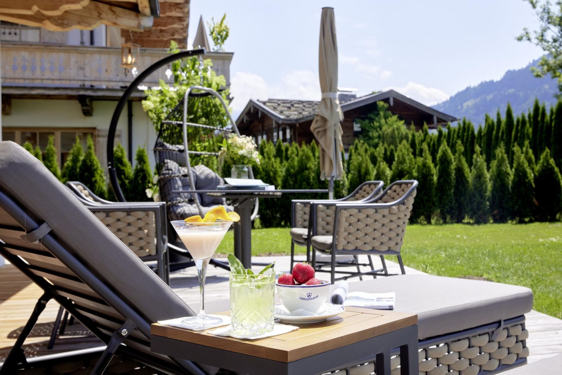 Private patio with sun loungers, hanging egg chair, and mountain views