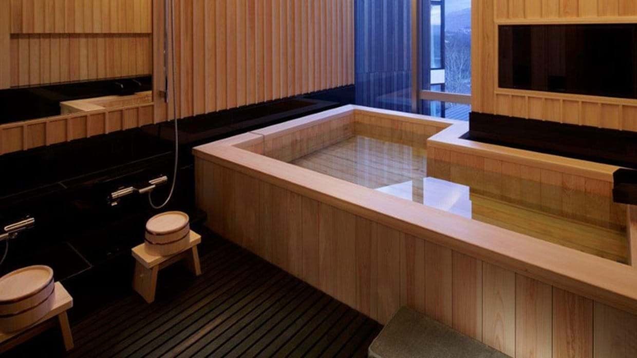 Hinoki wood soaking tub with handheld sprayer and floor seating