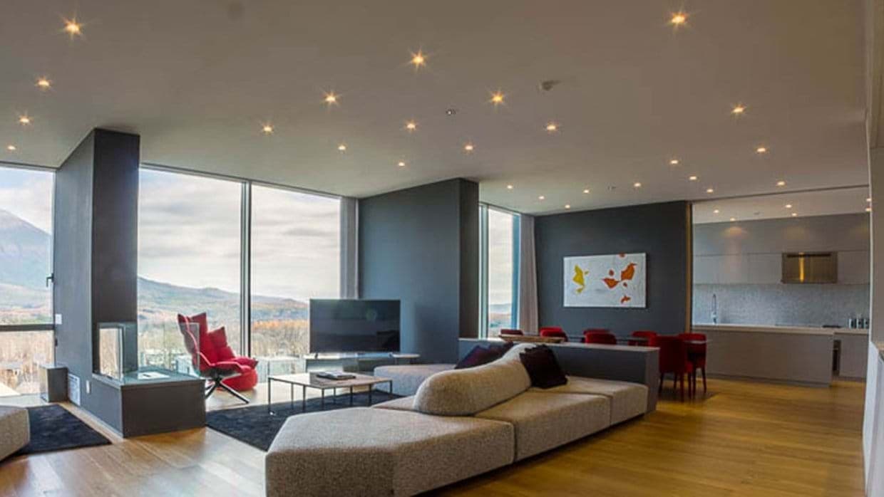 Open-plan living area with floor-to-ceiling mountain views and gas fireplace