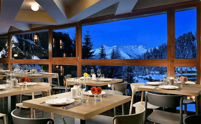 Dining area with floor-to-ceiling windows and alpine mountain views