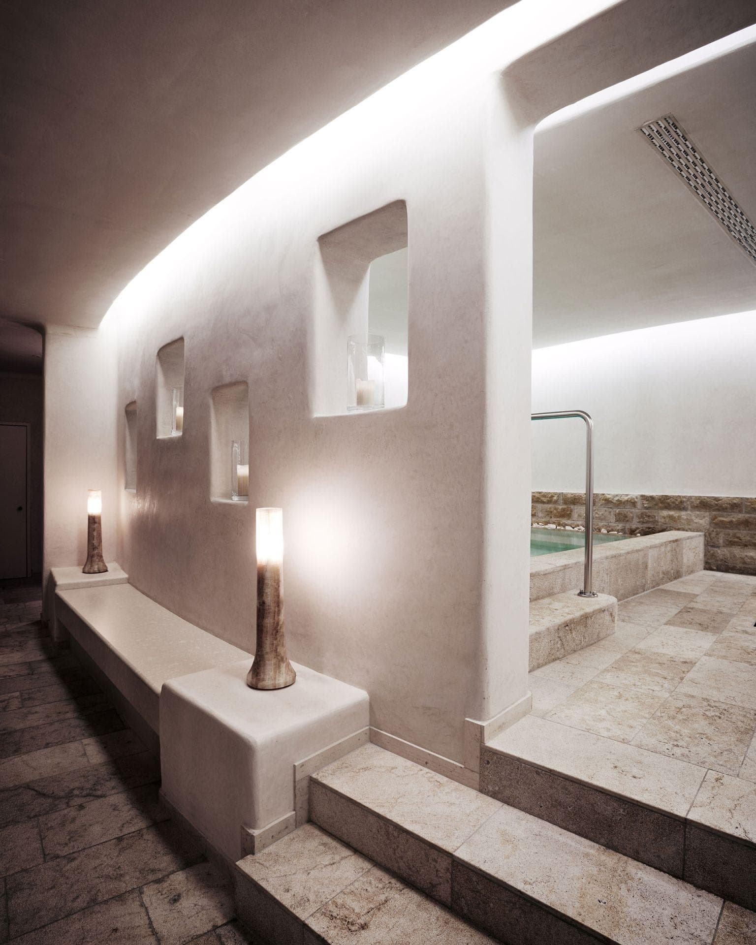Indoor spa area with heated stone bench and plunge pool