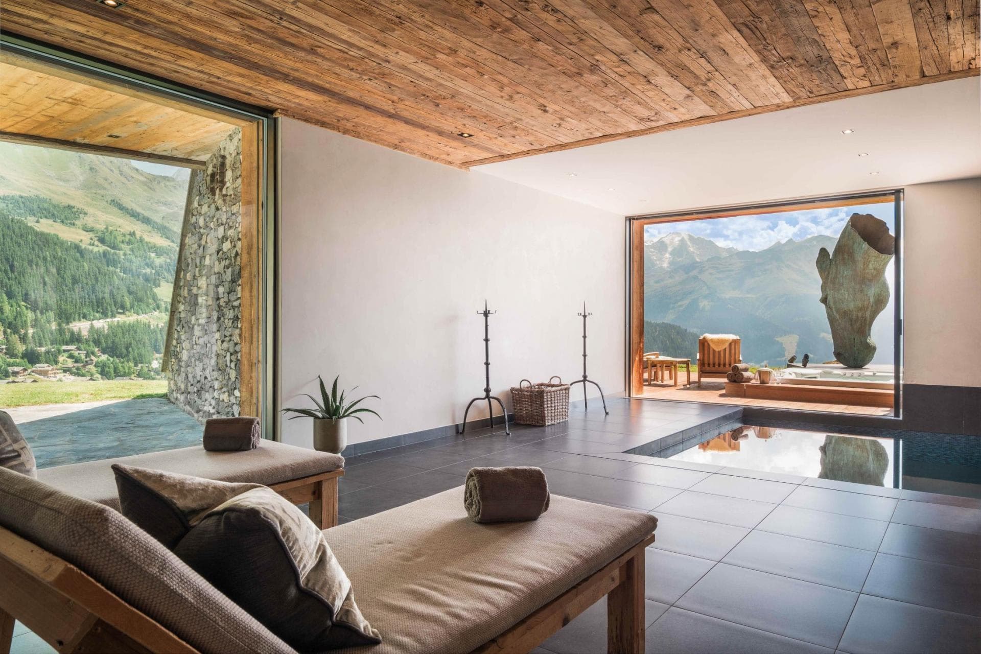Indoor spa area with pool, loungers, and floor-to-ceiling mountain views