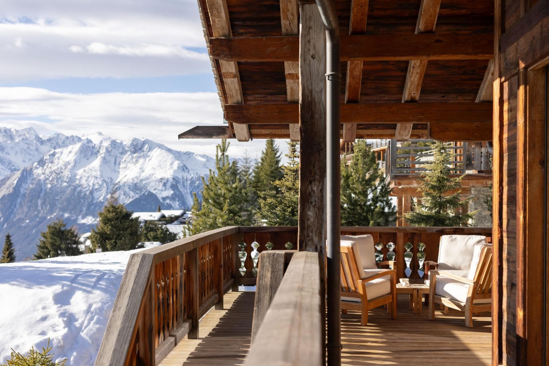 Covered balcony with armchair seating and panoramic mountain views