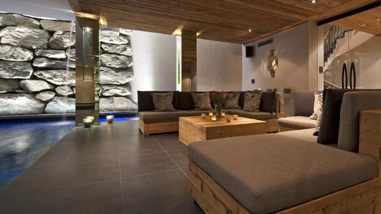 Indoor lounge area with sectional seating adjacent to heated pool